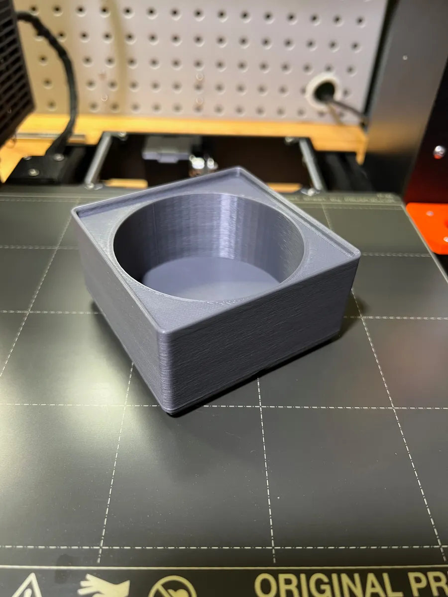 A 3D printed wash bottle holder designed for gridfinity sitting on top of a print bed